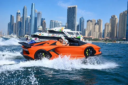 Orange Jet Car on the water beside the Dubai Marina skyline